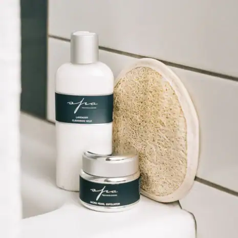 Lavender Cleansing Milk and Cream Set in Shower Lavender cleansing milk bottle and cream jar set displayed on a white shower ledge.